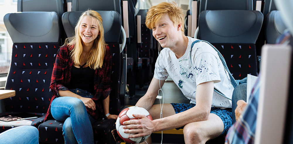 Zwei junge fröhliche Menschen sitzen in der Bahn