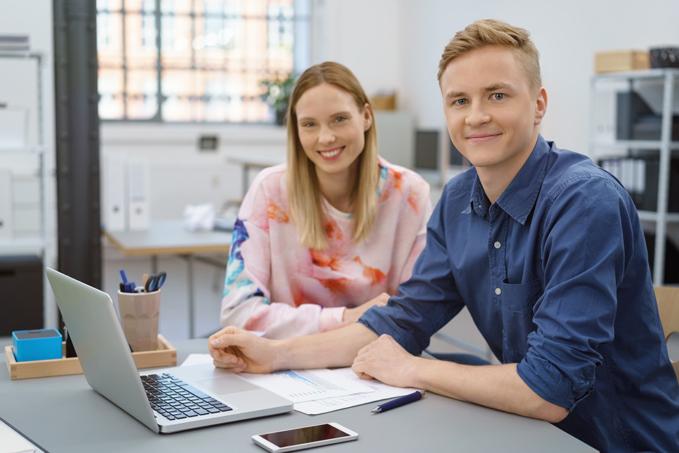 Junge Frau und junger Mann im Büro am Rechner sitztend