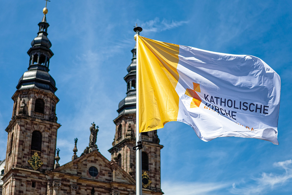 Wehende Fahne des Bistums Fulda vor Kirche