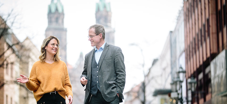 Zwei Personen im Vordergrund, im Hintergrund eine Kirche.