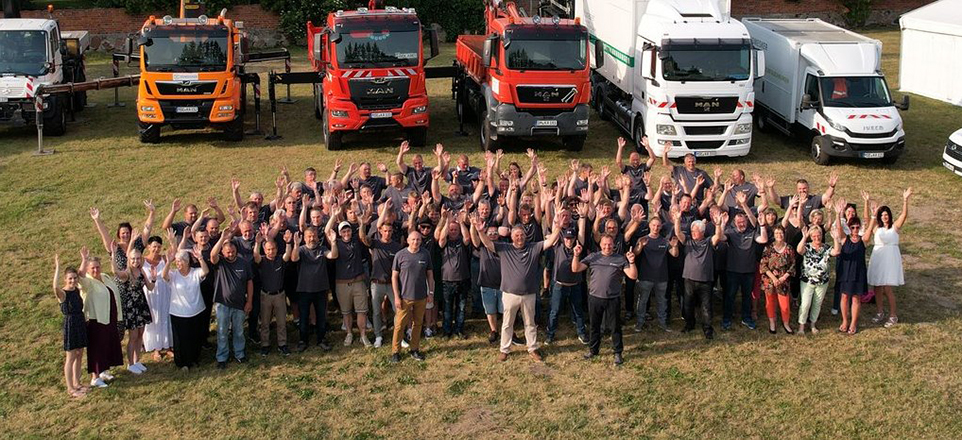 Große Personengruppe aus der Luft fotografiert. Im Hintergrund Dienstleistungsfahrzeuge.