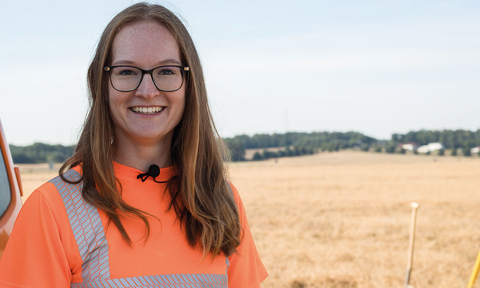 Mädchen mit Brille und orangen T-Shirt steht auch einem Feld.