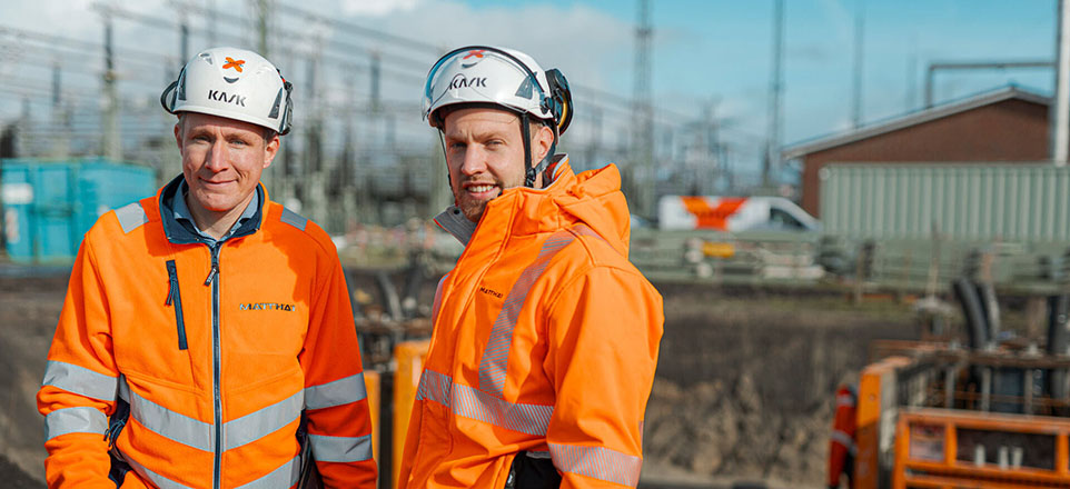 Mitarbeitende Matthäi Bauunternehmen in orangefarbener Schutzkleidung mit Helm