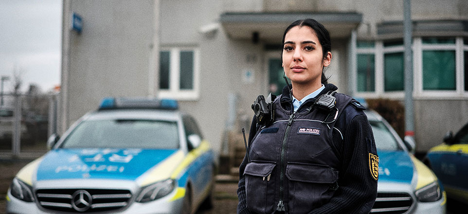 Polizistin in Uniform vor Einsatzwagen