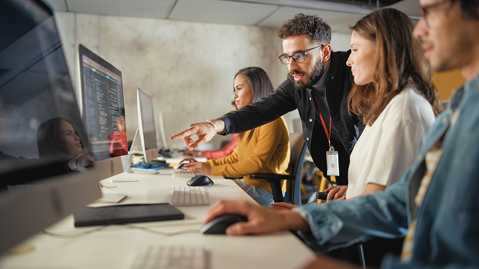 Personen sitzen vor Computerbildschirmen