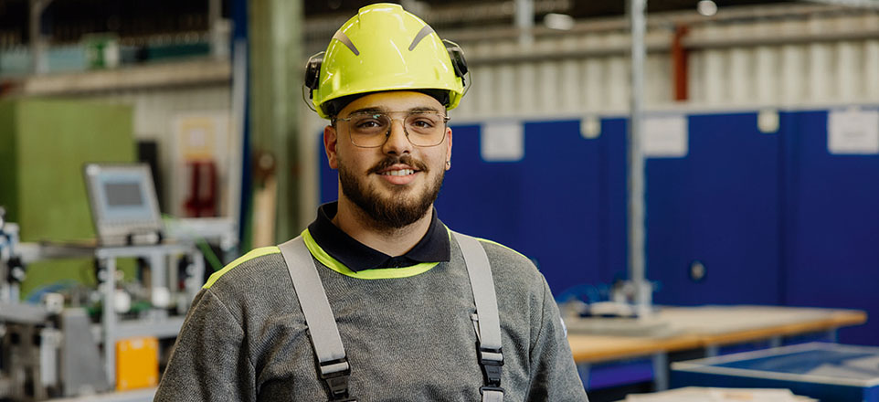 Auszubildender in Arbeitskleidung mit Helm