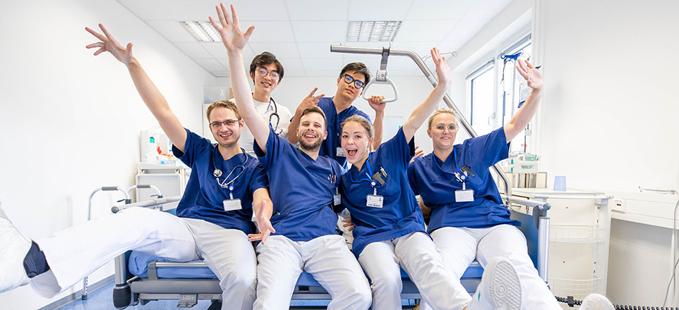 Junge Ärztinnnen und Ärzte auf Krankenbett.