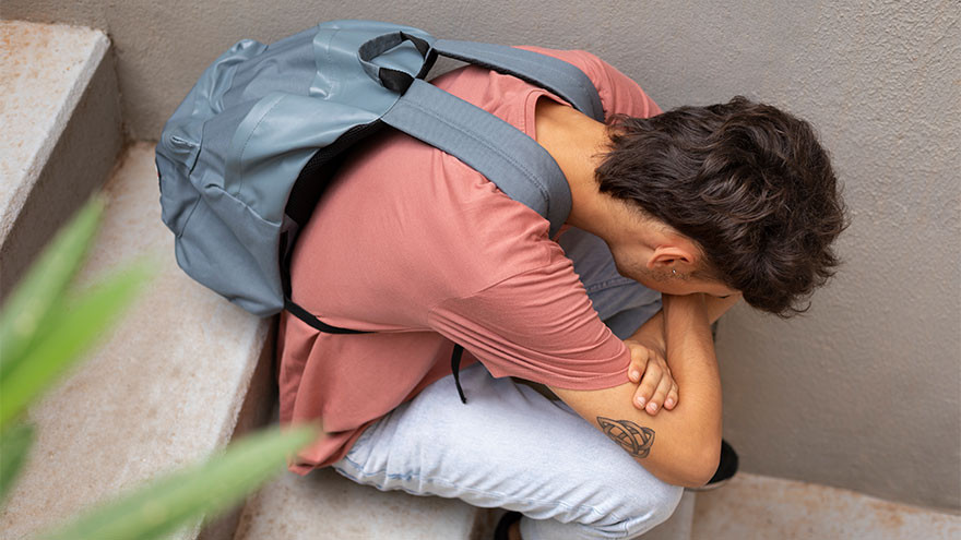 Trauriger junge sitzt auf einer Schultreppe. Bild von Freepik.