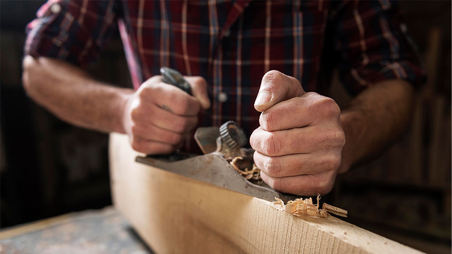 Mann, der mit Holz in der Werkstatt arbeitet. Bild von Freepik.