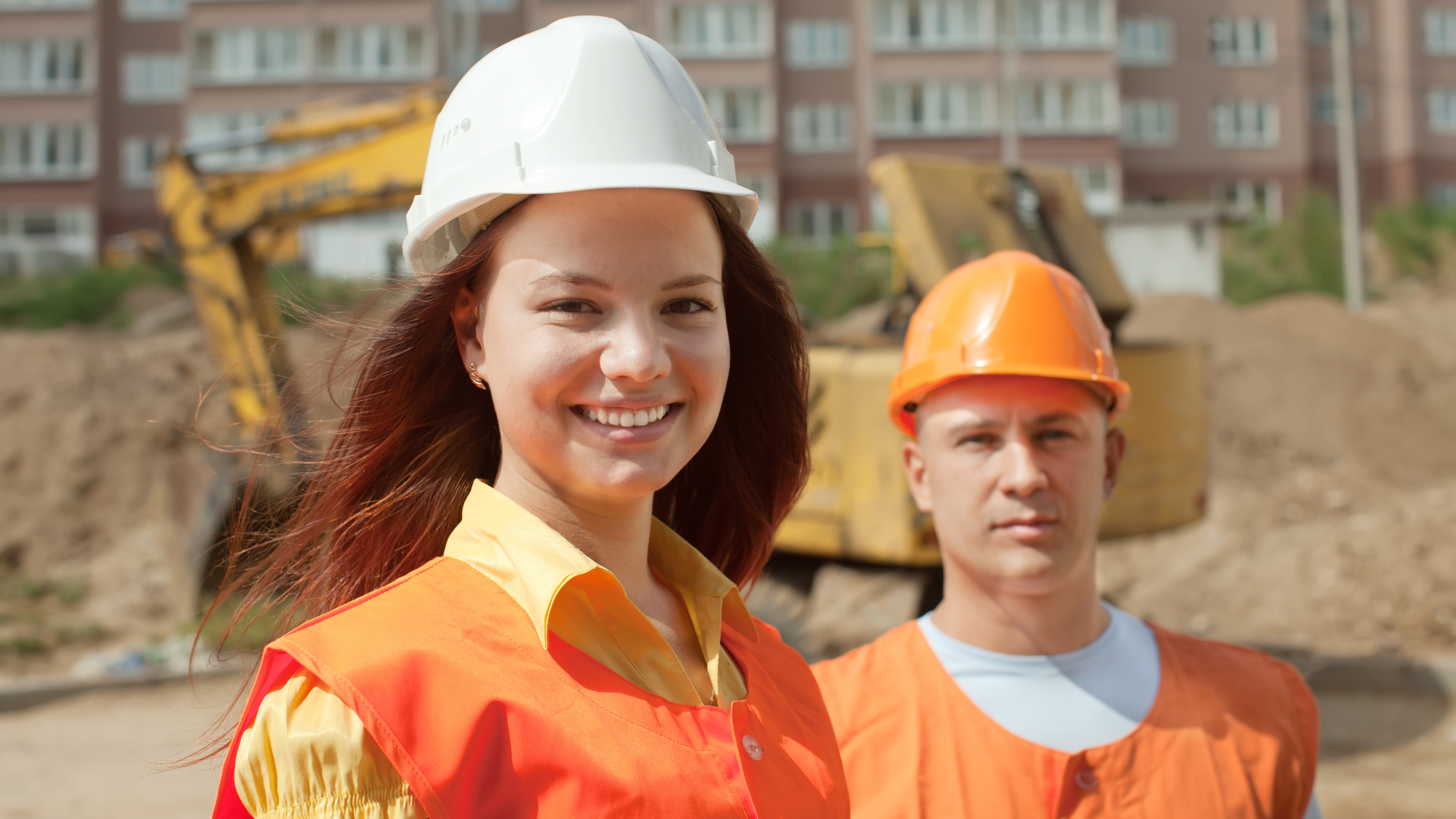 Bauarbeiterin und Bauarbeiter vor einer Bausetelle /freepik